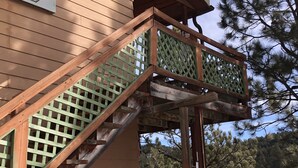 Un escalier en bois avec une rampe en treillis vert menant à un balcon.
