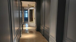 Ein Flur mit dunklen Wänden und einem glänzenden Boden, der zu einer Tür mit Fensterteil führt.
