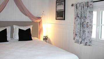 A bedroom with a bed, a nightstand, a lamp, and a window with curtains.