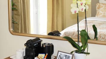 Un bureau en bois avec une machine à café, des tasses, un cadre photo et une orchidée en pot.