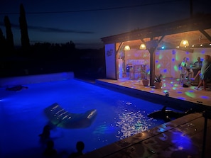 A swimming pool with a slide, a covered seating area, and a bar/lounge with people. - Les Rocailles (Lamonzie-Montastruc)