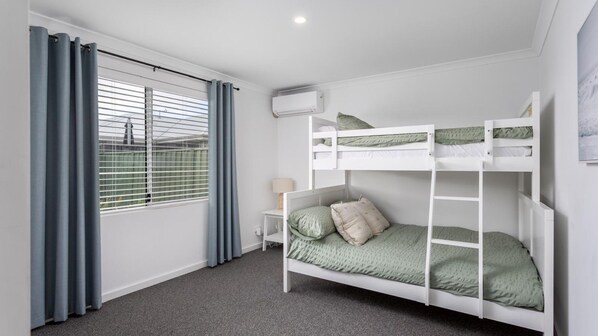 Habitación con literas, ventana, cortinas y unidad de aire acondicionado.