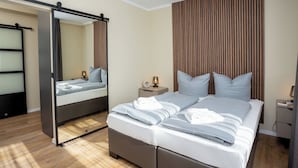 Ein modernes Schlafzimmer mit einem großen Bett, einem Nachttisch, einem Spiegel und Holzboden.
