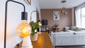 Un salon moderne avec une table basse en bois, une lampe blanche et un canapé.