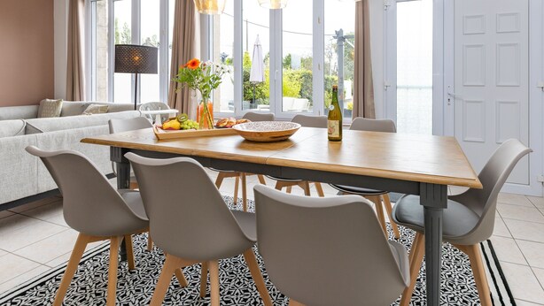 Un espace repas moderne avec une table en bois, des chaises grises et un vase de fleurs.