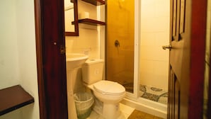A bathroom with a toilet, a shower, and a sink.