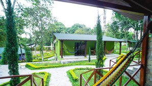 A courtyard with a hammock, a small building with a green roof, and a well-maintained garden.