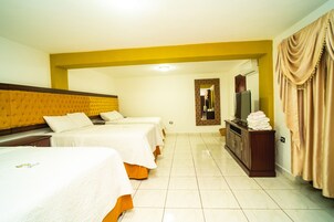 A hotel room with two beds, a TV, a mirror, and a bathroom visible in the background.