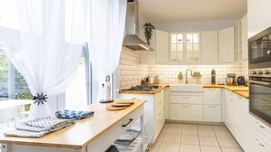 Et moderne køkken med hvide skabe, en træbordplade og en gaskomfur.