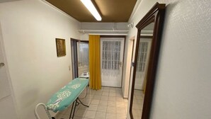 Une pièce comprenant un lit, une table de chevet, une chaise, une fenêtre avec des rideaux jaunes et un miroir au mur.