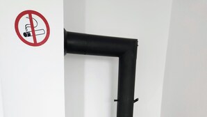 Un poêle à bois noir, doté d’une porte en verre, d’une cheminée et d’une grille métallique sur laquelle est posée une casserole.