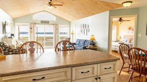 A spacious kitchen with a granite countertop, wooden chairs, and a ceiling fan. - Waterfront Cottage in Stanley Bridge—Bay Views, Sleeps 8, Near Cavendish (North Rustico)
