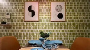 A dining area with a wooden table set for four, blue plates, cutlery, and glasses. Two framed artworks hang on the wall above the table. - SW Nishi-Waseda Building 202 (Tokyo)