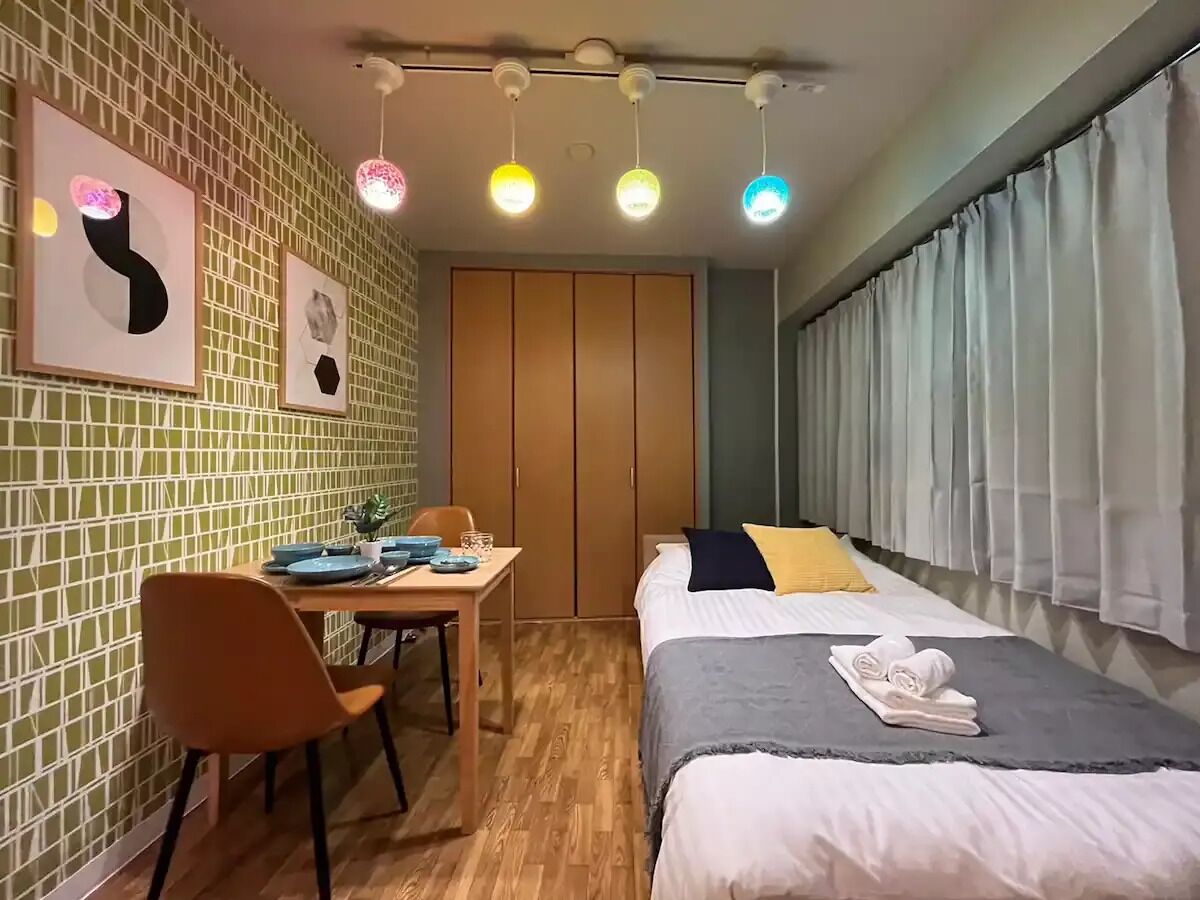 Habitación de hotel con cama, escritorio, sillas y ventana con cortinas.