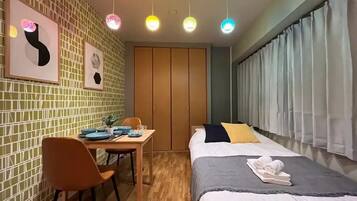 Habitación de hotel con cama, escritorio, sillas y ventana con cortinas.