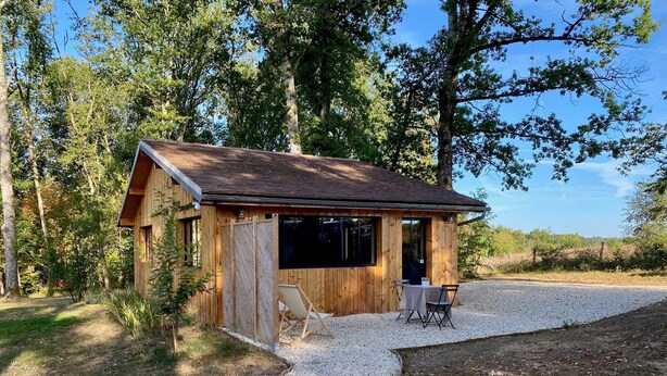 A wooden cabin with a gravel driveway, two chairs, and a table. - Coline's house pool view (Lamonzie-Montastruc)