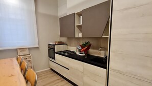 A modern kitchen with wooden cabinets, a black countertop, and a wooden dining table with chairs.