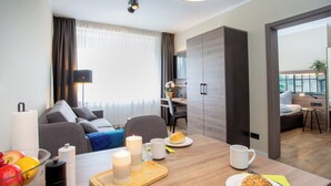 Una camera d'hotel moderna con angolo ristoro, divano, scrivania e letto.