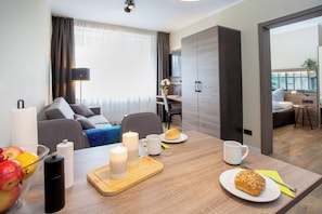 Ein modernes Hotelzimmer mit Essbereich, einer Couch, einem Schreibtisch und einem Bett.