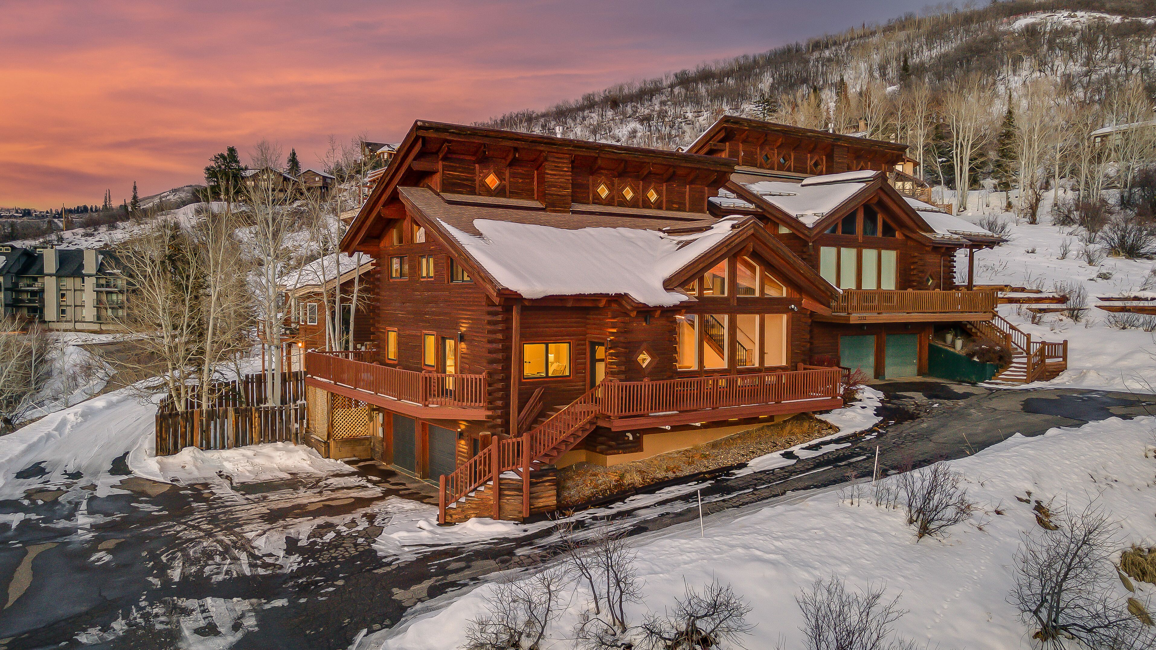 Une grande cabane en rondins à plusieurs niveaux, dotée d’un balcon et surplombant un paysage enneigé.