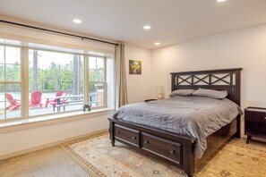 A bedroom with a large window, a bed, a nightstand, and a radiator.