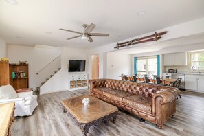 A spacious living room with a leather sofa, a wooden coffee table, and a television mounted on the wall.