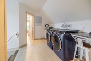 A laundry area with two front-loading washing machines, a drying rack, and a table with a sign that reads 'LAUNDRY'.