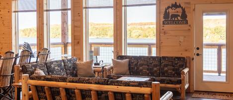 A cozy cabin interior with a wooden bench, a patterned sofa, and a welcome sign.