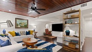A living room with a white sofa, blue and yellow cushions, a wooden coffee table, and a blue and white striped rug.