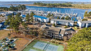 Un port de plaisance abritant de nombreux bateaux, un court de tennis et plusieurs bâtiments au design moderne.