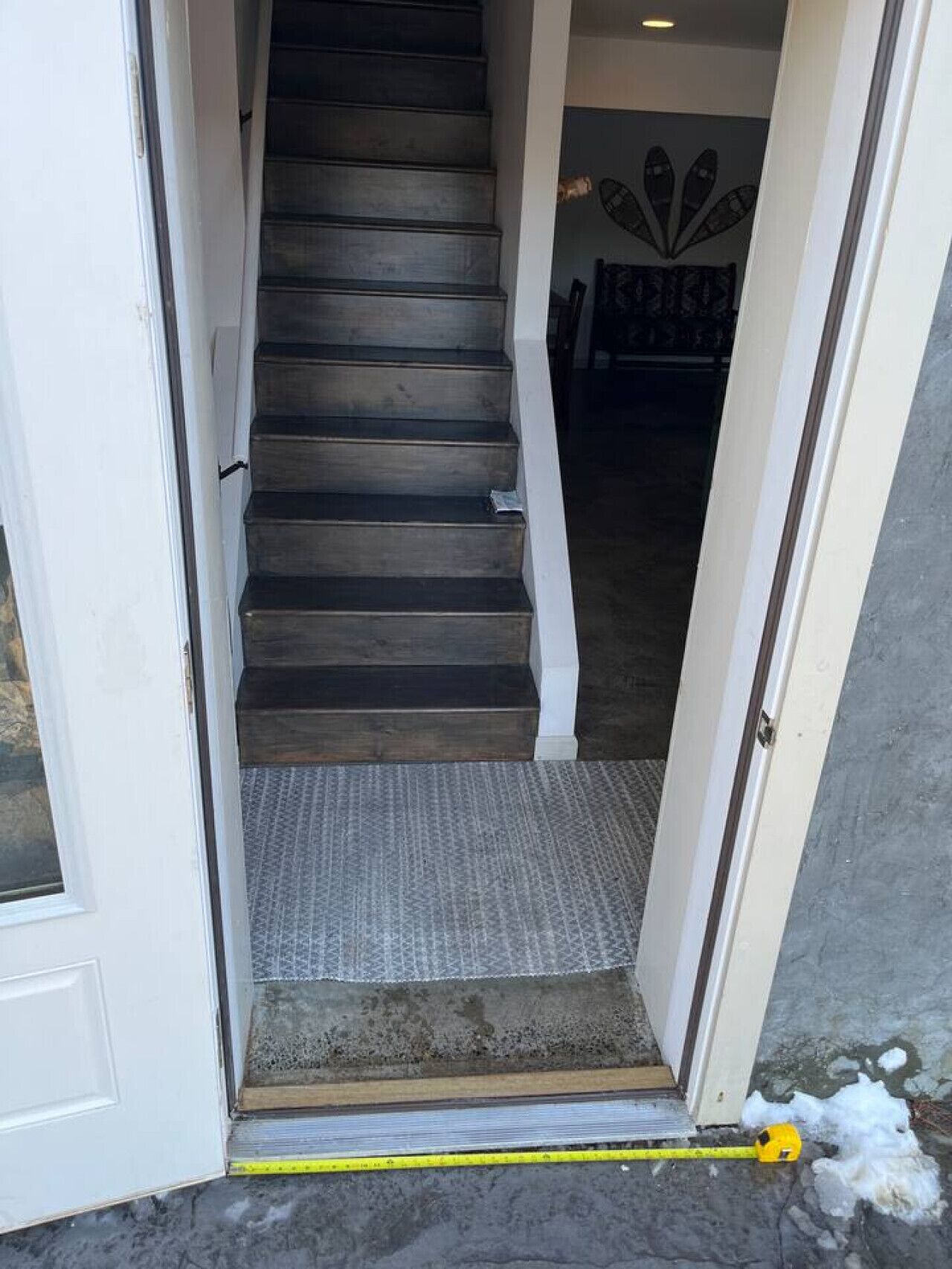 Un escalier menant à un espace intérieur doté d’un tapis à motifs et d’un cadre de porte.