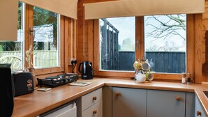 A kitchen with wooden cabinets, a stove, and a coffee maker. - 2 bedroom accommodation in West Walton (West Walton)