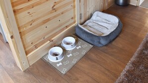A wooden interior with a pet bed, two bowls, and a vase. - 2 bedroom accommodation in West Walton (West Walton)
