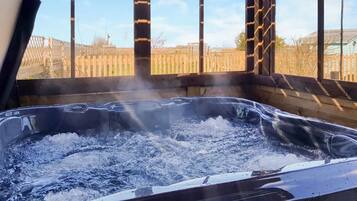 Un jacuzzi con un cerramiento de madera y un cielo despejado al fondo.