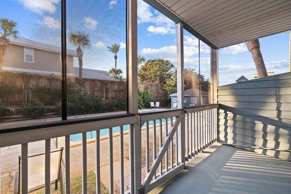 A covered outdoor area with a view of a pool and a building in the background.