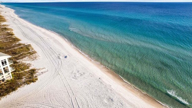 Ein Luftbild eines Strandes mit klarem türkisblauem Wasser und einem sandigen Ufer.