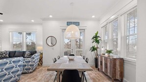 A modern dining area with a wooden table, black chairs, and a hanging light fixture. - Golf Cart~ Heated Pool~ Bikes ~ 5 min to Beach! (Inlet Beach)