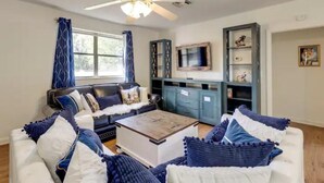 A living room with a sofa, coffee table, and a TV on a cabinet. - Pennyfarthing Farm South (Ocala)