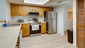 A compact kitchen with wooden cabinets, stainless steel appliances, and a skylight. - Pennyfarthing Farm South (Ocala)