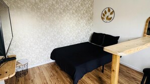 A bedroom with a bed, a desk, and a wall-mounted decorative item.