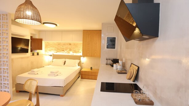 Een moderne slaapkamer met een groot bed, nachtkastjes, een bureau en een hanglamp.