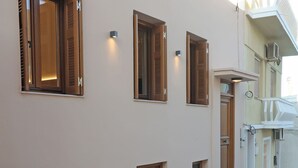 Een gebouw met meerdere ramen en deuren, een straat met stenen tegels, en een bloempot met plant.