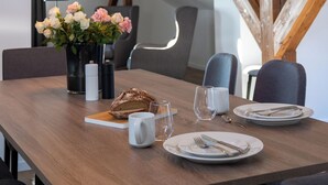 Une table à manger avec une miche de pain, un vase de fleurs et une bougie.