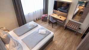 Habitación de hotel moderna con cama, escritorio, televisor y espejo.