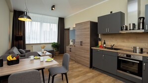 Una cocina moderna con horno integrado y comedor con mesa y sillas de madera.