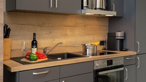 Una cocina moderna con armarios grises, encimera de madera, un lavabo, una estufa y una cafetera.