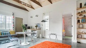 Amplia sala de estar con un tapete naranja grande, muebles modernos y una cocina visible a través de una puerta abierta.