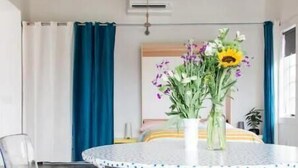 Una habitación moderna con una mesa redonda blanca, sillas transparentes y una alfombra naranja vibrante.