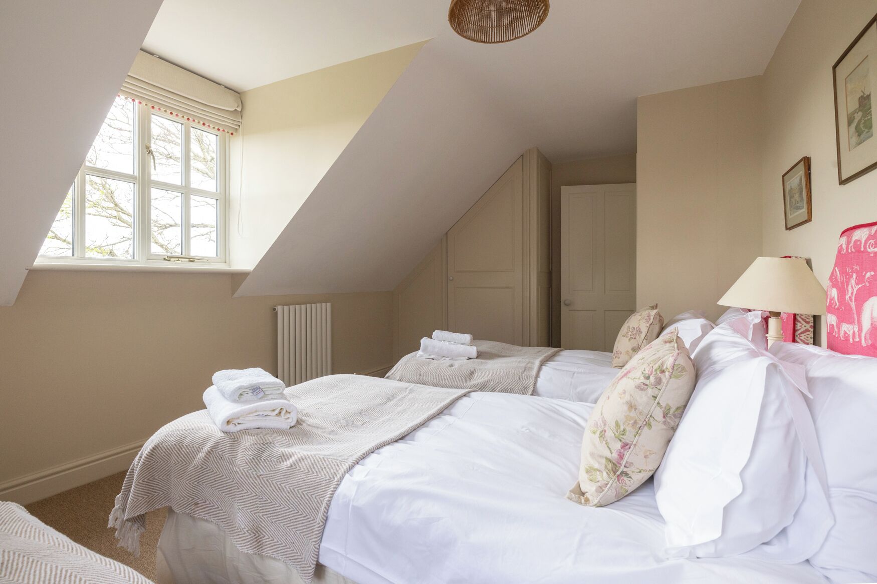 Une chambre avec deux lits, un radiateur, une fenêtre et une lampe.