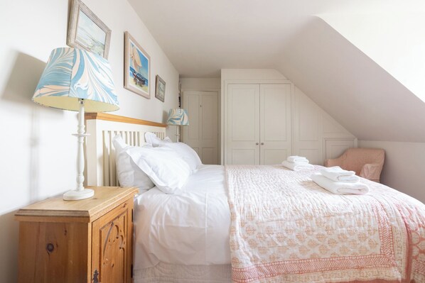 A bedroom with a bed, a nightstand, a lamp, a chair, and a wardrobe. - Stunning Riverside Cottage with Breathtaking Views, 1 mile from Snape Maltings (Woodbridge)